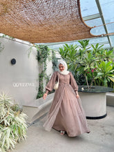 Woman wearing YEZWE brown skirt and top modest party wear in a lush indoor garden setting